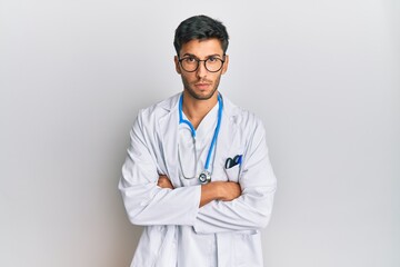 Young handsome man wearing doctor uniform and stethoscope skeptic and nervous, disapproving expression on face with crossed arms. negative person.