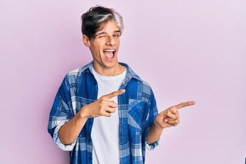 Young hispanic man pointing with fingers to the side winking looking at the camera with sexy...