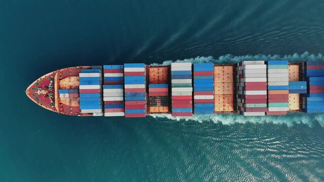 Aerial top view of smart cargo ship carrying container and running very fast for export cargo from container yard port to custom ,Contrail line in the ocean by large ship very fast. 