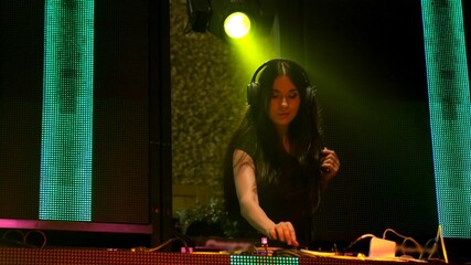 DJ on stage in disco night club mixing techno music beat . Nightlife and dance party .