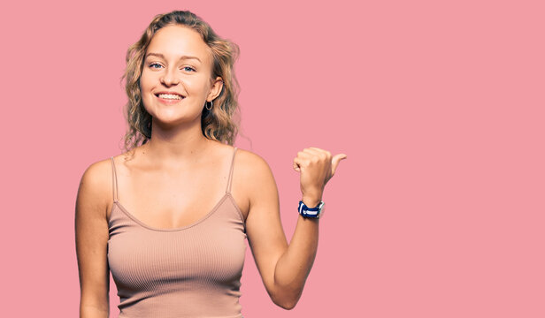 Beautiful caucasian woman wearing casual clothes smiling with happy face looking and pointing to the side with thumb up.