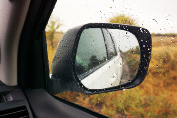 Rearview mirror against the background of an autumn landscape. Traveling by car off-road. View from...
