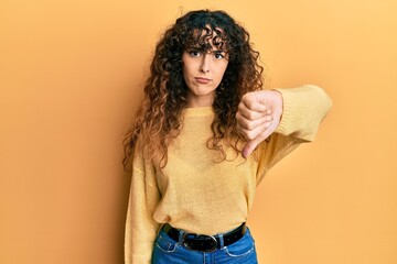 Young hispanic girl wearing casual clothes looking unhappy and angry showing rejection and negative with thumbs down gesture. bad expression.