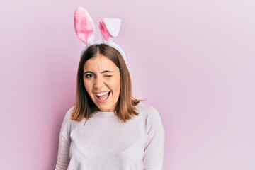 Young beautiful woman wearing cute easter bunny ears winking looking at the camera with sexy...