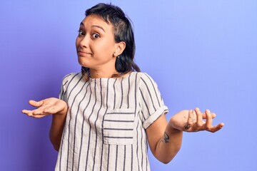 Young woman wearing casual clothes clueless and confused expression with arms and hands raised....