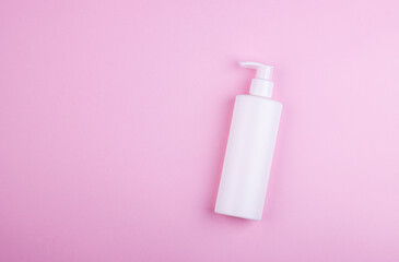 Body care product in a white bottle on a pink pastel background