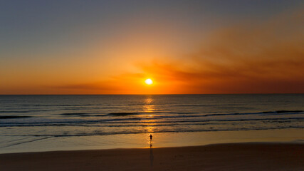 Fototapeta premium Person standing on beach at sunrise 