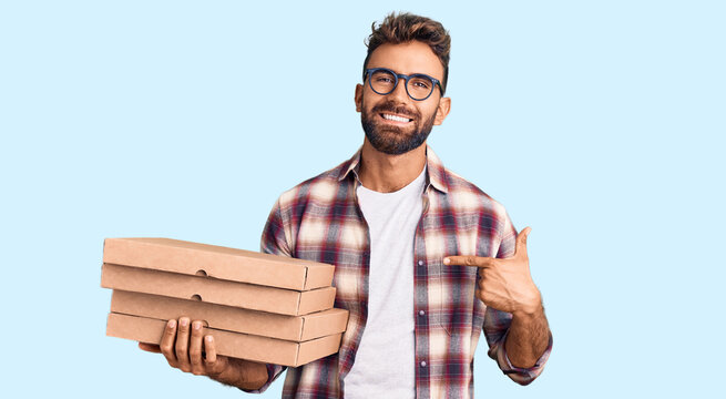 Young hispanic man holding delivery pizza box pointing finger to one self smiling happy and proud
