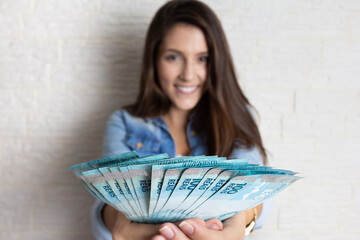 Happy pretty woman holding brazilian banknotes currency. Finance, investment, offer, debt, sale, progress concept.