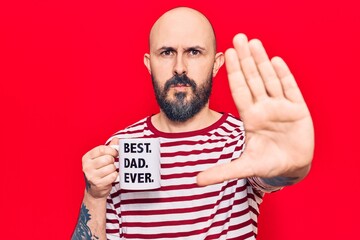 Young handsome man drinking mug of coffe with best dad ever message with open hand doing stop sign with serious and confident expression, defense gesture