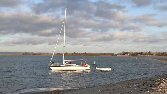 Sailing Boat heading out from East Head near West Wittering in West Sussex with no sail but under power.