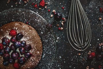Berries on brownie with plate powdered sugar and egg beater