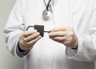 A doctor putting an end to Covid-19 corona virus pandemic isolation lockdown by opening the padlock