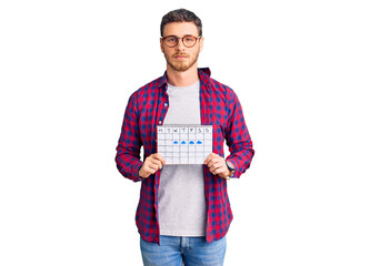 Handsome young man with bear holding travel calendar thinking attitude and sober expression looking self confident
