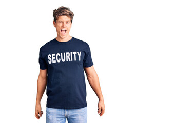 Young handsome man wearing security t shirt winking looking at the camera with sexy expression,...