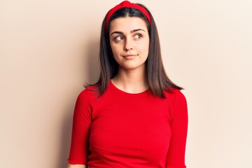 Young beautiful girl wearing casual t shirt and diadem smiling looking to the side and staring away thinking.