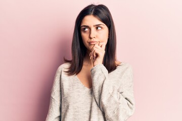 Young beautiful girl wearing casual sweater thinking concentrated about doubt with finger on chin and looking up wondering