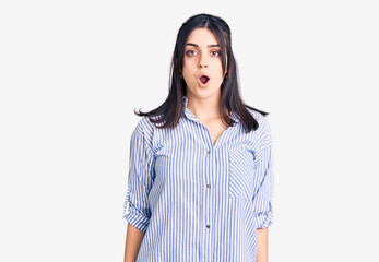 Fototapeta premium Young beautiful girl wearing striped shirt scared and amazed with open mouth for surprise, disbelief face