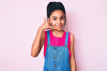 Young african american girl child with braids wearing casual clothes over pink background smiling doing phone gesture with hand and fingers like talking on the telephone. communicating concepts.