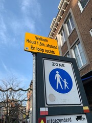 Road sign for corona prevention and social distancing. Keep 1,5 meters distance (houd afstand).  Walk right (En loop rechts). Roermond, Limburg, Netherlands 

