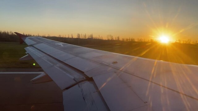 Leaving Saint Petersburg, Russia, aircraft wing seen from airplane window at sunset, passenger plane taking off.
