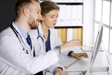 Red-bearded doctor with female colleague discussing current disease therapy while sitting at...