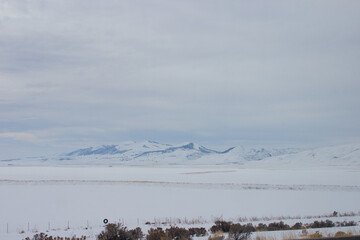 Steppes, fields, mountains covered with snow after sunset. Endless snowy expanses with valleys and mountains on a cloudy winter day. Utah, USA