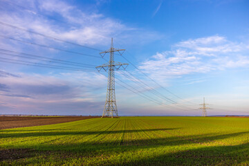 Fototapeta na wymiar Strommasten Überlandleitungen stehen auf dem Acker Feld Hochvolt Stromleitung