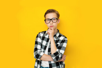 Handsome teen boy thinking gesture on yellow background