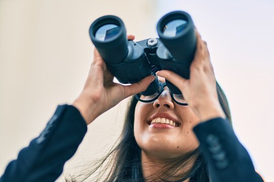 Young hispanic businesswoman looking for new opportunity using binoculars at the city.