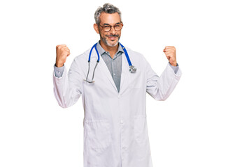 Middle age grey-haired man wearing doctor uniform and stethoscope screaming proud, celebrating victory and success very excited with raised arms