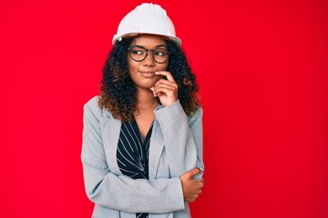 Young african american woman wearing architect hardhat thinking concentrated about doubt with...