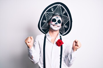 Man wearing day of the dead costume over white very happy and excited doing winner gesture with arms raised, smiling and screaming for success. celebration concept.