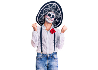 Man wearing day of the dead costume over background very happy and excited doing winner gesture with arms raised, smiling and screaming for success. celebration concept.