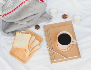Cozy autumn or winter concept. cup of coffee and bread for breakfast in the white linen bed with...