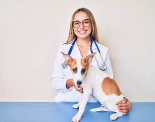 Young beautiful blonde veterinarian woman checking dog health smiling with a happy and cool smile on face. showing teeth.