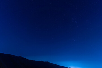 night view of city and starry sky from mountainside