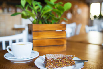 Coffee mug on wooden table, sweet wafer on a plate. Close-up.
