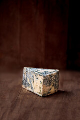 Blue cheese Gorgonzola on a rustic wooden background. Mold cheese with copyspace. Fresh  typical italian blue cheese close up.
