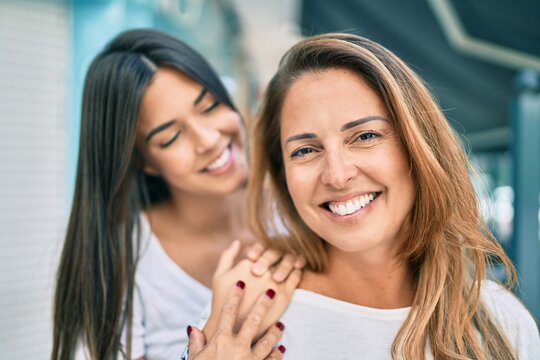 Beautiful hispanic mother and daughter smiling happy standing at the city.