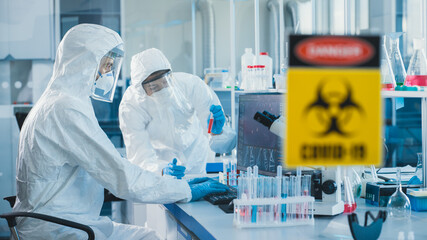 Medical Laboratory Team of Microbiology Scientists Wearing Sterile Coveralls, Face Shields and...