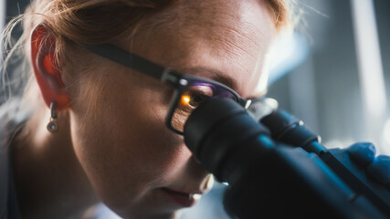 In Bright Medical Science Laboratory: Beautiful Microbiologist Wearing Glasses Looks Under...