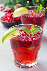 Homemade lingonberry and lime punch or limeade in glass, christmas tree decoration with bokeh, vertical