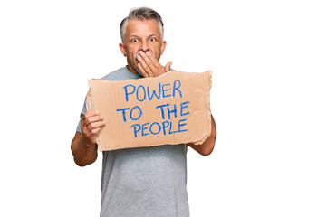 Middle age grey-haired man holding power to the people banner covering mouth with hand, shocked and afraid for mistake. surprised expression