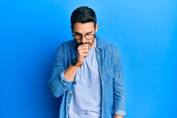 Young hispanic man wearing casual clothes and glasses feeling unwell and coughing as symptom for cold or bronchitis. health care concept.