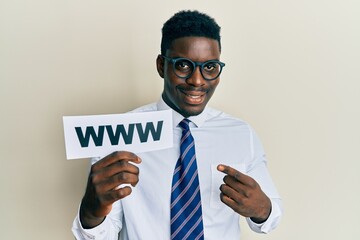 Handsome black man holding www on paper smiling happy pointing with hand and finger