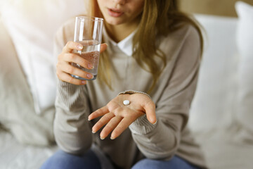 Close-up woman holding pills time to take medications, cure for headache. Medicine concept during self isolation and Coronavirus pandemic