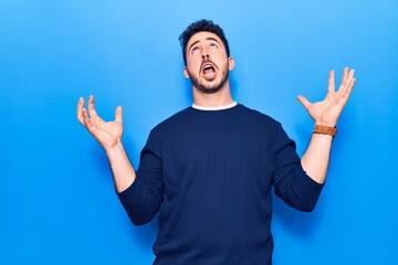 Naklejka premium Young hispanic man wearing casual clothes crazy and mad shouting and yelling with aggressive expression and arms raised. frustration concept.
