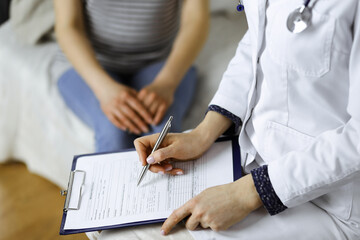 Unknown woman doctor and patient discussing current health examination while sitting in cozy living...