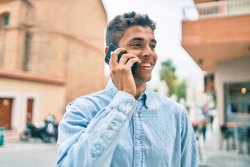 Young latin man smiling happy talking on the smartphone walking at the city.